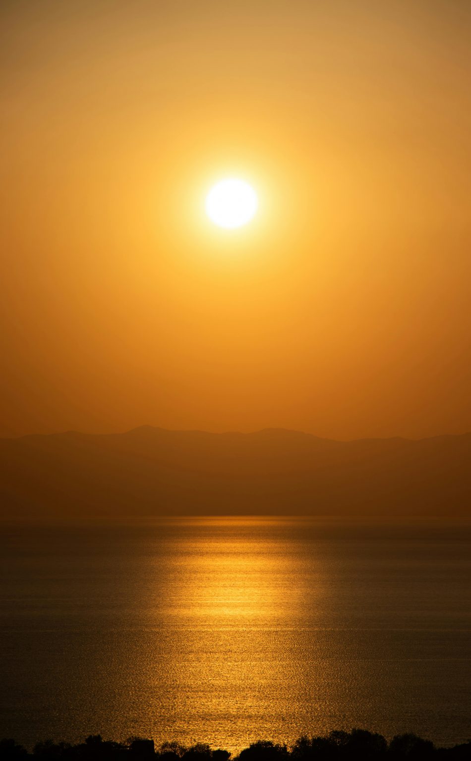 A stunning golden sunset over a tranquil sea with warm, dramatic lighting.